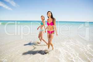 Female friends holding hands on beach