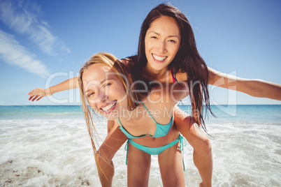 Woman giving piggy back to her female friend