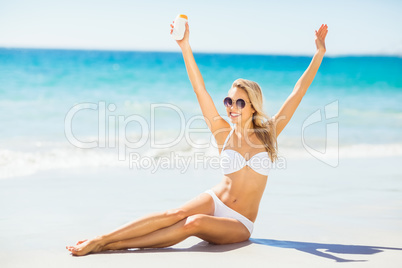 Woman posing with sun cream on beach