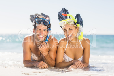 Young couple wearing diving mask lying on beach