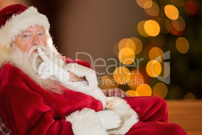Composite image of Santa is sitting and looking the camera