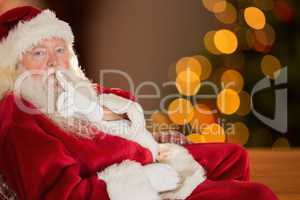 Composite image of Santa is sitting and looking the camera
