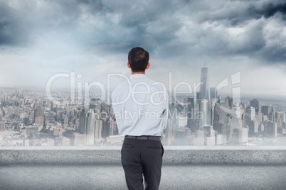 Composite image of businessman is looking the cityscape