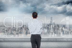 Composite image of businessman is looking the cityscape