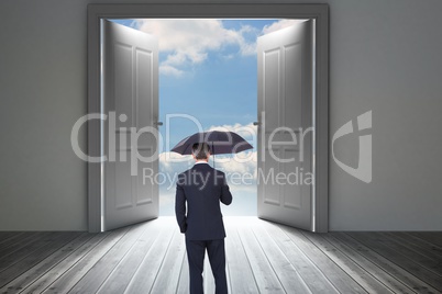 Composite image of businessman is holding an umbrella