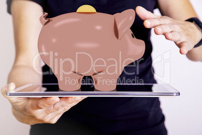 Hand holding tablet PC with piggy bank