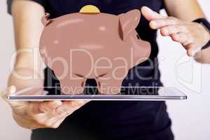 Hand holding tablet PC with piggy bank