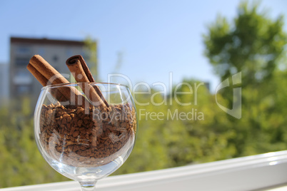 cinnamon sticks in a glass of wine with granulated coffee, daylight