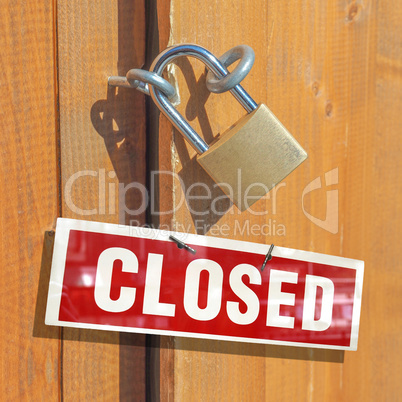 Padlock on a wood door with closed sign