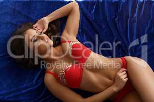 Image of sexy girl lying on blue velvet bed sheet