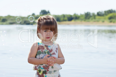 Cute little girl posing with soap bubbles at lake