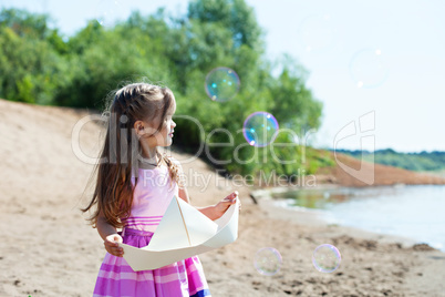 Nice little girl playing with paper boat