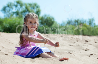 Cute curly-haired girl plays with sand