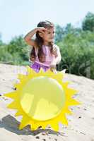 Curious young girl posing with paper sun