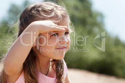 Image of cute little girl covers her eyes from sun