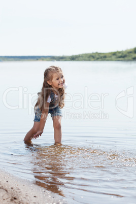 Cheerful little girl playing in lake