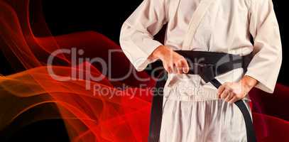 Composite image of mid section of fighter tightening karate belt