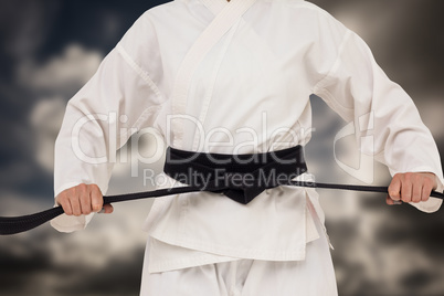 Composite image of fighter tightening karate belt