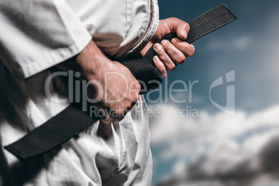 Composite image of fighter tightening karate belt