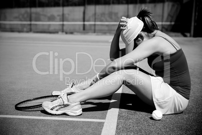 Upset tennis player sitting on court