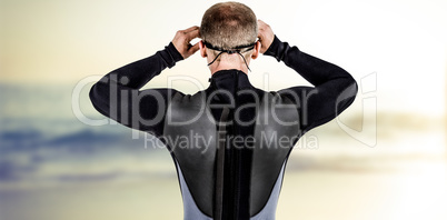 Composite image of rear view of swimmer in wetsuit wearing swimm