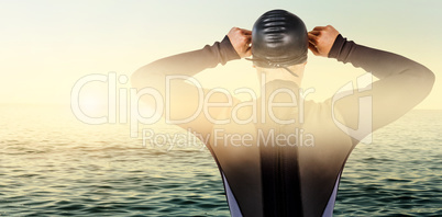 Composite image of rear view of swimmer in wetsuit wearing swimm