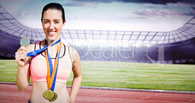 Composite image of portrait of happy sportswoman showing her med