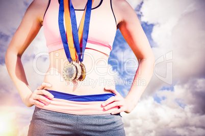 Composite image of portrait of sporty woman chest holding medals