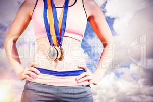 Composite image of portrait of sporty woman chest holding medals