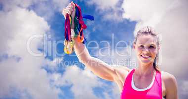 Composite image of portrait of happy sportswoman raising her med