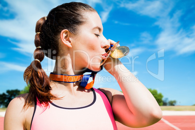 Composite image of portrait of sportswoman kissing her medals