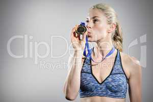 Composite image of happy female athlete kissing medal