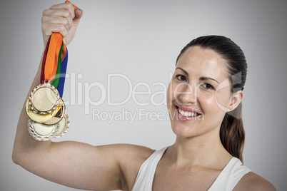 Composite image of female athlete posing with gold medals after Composite image of female athlete posing with gold medals after