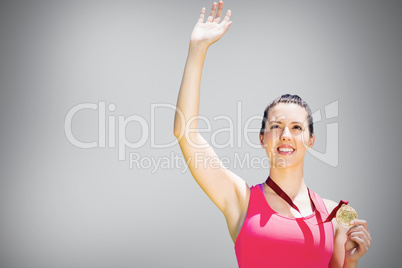 Composite image of athletic woman smiling and holding a medal