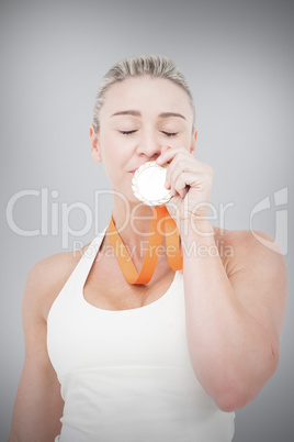 Composite image of happy female athlete kissing medal