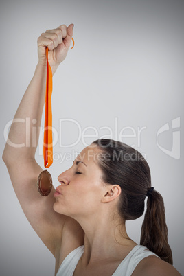 Composite image of happy athlete kissing medal Composite image of happy athlete kissing medal