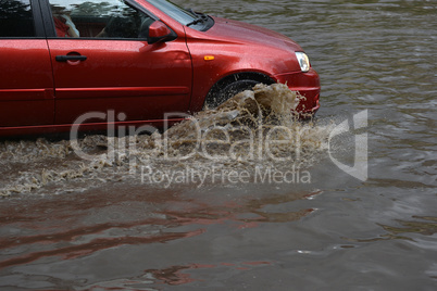 Car rides in heavy rain on a flooded road