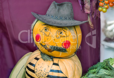Funny statue made from two pumpkins in the form of a man in a ha