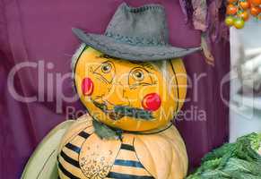 Funny statue made from two pumpkins in the form of a man in a ha