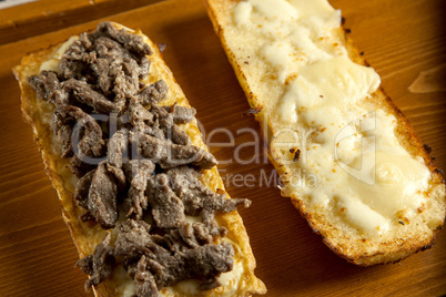 toasted open faced beef steak sandwich with melted mozzarella ch