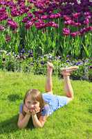 little girl lies on the grass near the tulips