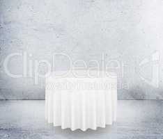 Empty round table with tablecloth isolated on concrete background