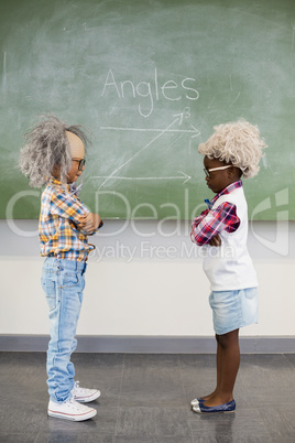 Kids wearing wig standing face to face in classroom