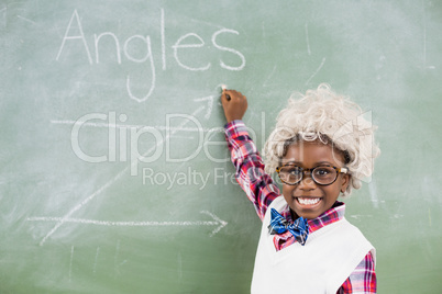 Portrait of schoolboy wearing wig doing mathematics on chalkboard in classroom