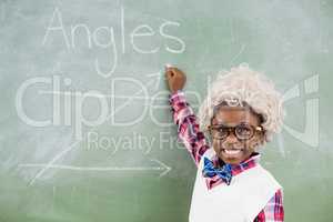 Portrait of schoolboy wearing wig doing mathematics on chalkboard in classroom