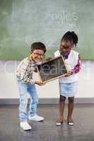 Portrait of two smiling school kids holding slate in classroom
