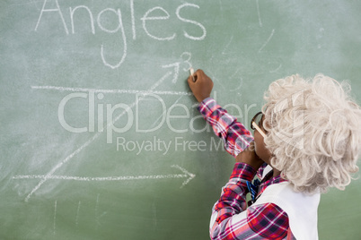 Schoolboy doing mathematics on chalkboard in classroom
