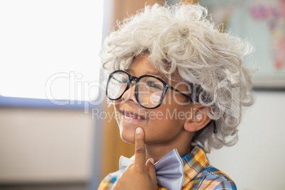 Thoughtful schoolboy wearing wig in classroom