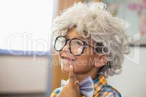 Thoughtful schoolboy wearing wig in classroom