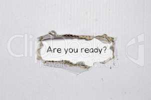The word are you ready appearing behind torn paper.